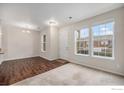 Bright living room featuring hardwood floors and plush carpet, illuminated by natural light from large windows at 12774 Leyden St # D, Thornton, CO 80602