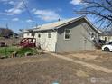 View of the cozy home featuring a fenced yard, red porch, and some mature landscaping at 1306 Main St, Platteville, CO 80651