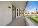 Welcoming front porch of a beautifully maintained home showcasing a gray front door, brick wall, and American flag at 1643 Vivian St, Longmont, CO 80501