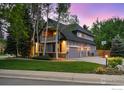 Large home featuring three-car garage, with mature trees and manicured lawn at 1775 Rockies Ct, Lafayette, CO 80026