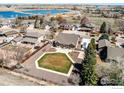 Aerial view of the backyard with fenced yard, green lawn, a lake, and neighborhood at 2101 Breckenridge Dr, Berthoud, CO 80513