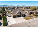 Aerial view of a home with a three-car garage and large driveway showcasing the surrounding neighborhood and mountain views at 2101 Breckenridge Dr, Berthoud, CO 80513