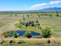 Aerial shot of a large property with ponds, green fields, multiple buildings, and mountain views at 5196 Oxford Rd, Longmont, CO 80503