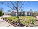 Well-maintained home featuring a large front yard with mature landscaping and a welcoming entrance at 1002 Stage Dr, Fort Lupton, CO 80621