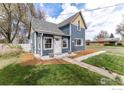 Quaint two-story home with blue siding, white trim, and a neatly landscaped yard with mulch at 1031 N 4Th St, Berthoud, CO 80513