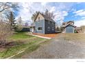 Two-story house with blue siding, a gravel driveway, and a detached garage in a spacious yard at 1031 N 4Th St, Berthoud, CO 80513