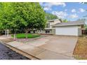 Well-maintained split-level home with mature tree, landscaped front yard, and large driveway leading to garage at 1518 Vivian St, Longmont, CO 80501