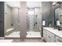 Luxurious bathroom featuring dual glass-enclosed showers, elegant tiling, and contemporary fixtures with a double vanity at 16392 Spanish Peak Way, Broomfield, CO 80023