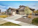Beautiful home exterior featuring a two-car garage, stone accents, and a well-maintained lawn at 16392 Spanish Peak Way, Broomfield, CO 80023