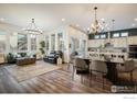 Open-concept living area with elegant lighting, hardwood floors, and large windows that provide ample natural light at 16392 Spanish Peak Way, Broomfield, CO 80023