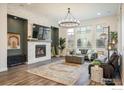 Bright living room with a stone fireplace, modern chandelier, and large windows at 16392 Spanish Peak Way, Broomfield, CO 80023