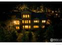 Exterior home elevation at night featuring many windows and mature evergreens at 1782 Tulip Tree Pl, Castle Rock, CO 80108