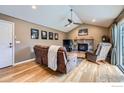 Cozy living room boasts vaulted ceilings, a ceiling fan, a stone fireplace, and hardwood floors at 357 W Harper St, Louisville, CO 80027