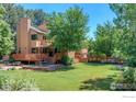 Backyard showcasing a multilevel deck, manicured lawn, mature trees and patio seating at 3895 Norwood Ct, Boulder, CO 80304