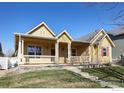 Charming yellow home with a covered front porch and well-maintained lawn at 4215 Bella Vista Dr, Longmont, CO 80503