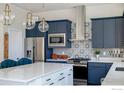 Modern kitchen featuring blue cabinets, stainless steel appliances, a large island, and stylish pendant lighting at 438 Meridian Ln, Superior, CO 80027