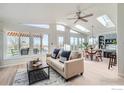 Bright living room featuring a ceiling fan, skylights, and large windows leading to an outdoor deck at 5855 Rustic Knolls Dr, Boulder, CO 80301