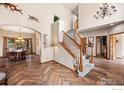 Elegant foyer with a curved staircase, wood floors, and views into the dining room at 7959 Nile Ct, Arvada, CO 80007