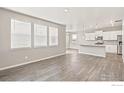 Open-concept living and kitchen area featuring luxury vinyl plank flooring and lots of natural light at 864 Leeward St, Lochbuie, CO 80603