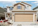 Well-maintained two-story home featuring a two-car garage and covered porch under a sunny sky at 10433 Forester Pl, Longmont, CO 80504