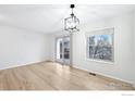 Bright living room featuring hardwood floors, a modern light fixture, a window and sliding door to the outside at 1383 W 88Th Ave # 307, Thornton, CO 80260