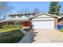 Two-story home with brick and siding, featuring a two-car garage, manicured bushes and a red front door at 1395 Abilene Dr, Broomfield, CO 80020