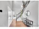 Bright foyer with hardwood floors, staircase, console table, and decorative mirror at 399 Ellie Way, Berthoud, CO 80513
