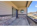 Inviting front porch with stone accents, modern lighting, and views of the neighborhood at 399 Ellie Way, Berthoud, CO 80513