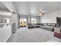 Spacious living room with plush carpeting, large sectional sofa, ceiling fan, and sliding glass doors at 399 Ellie Way, Berthoud, CO 80513