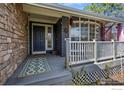 Inviting front porch with stone accents, white railing, and a decorative rug leading to the front door at 5397 Wild Dunes Ct, Boulder, CO 80301