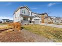 Attractive two-story home with grey siding, a porch, and three-car garage at 806 Flora View Dr, Erie, CO 80516