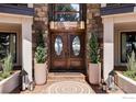 Inviting front entrance with double wooden doors, stone accents, and decorative planters at 10690 County Road 1, Longmont, CO 80504