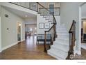 Inviting foyer with hardwood floors, staircase with iron railings, and view into adjoining rooms at 1321 Onyx Cir, Longmont, CO 80504
