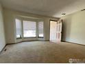 Inviting living room featuring large window, natural light, and neutral carpeting at 1525 Peterson Pl, Longmont, CO 80501