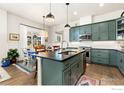 Well-lit kitchen with stainless steel appliances, dark countertops, and a view to the dining area at 174 High Point Dr, Longmont, CO 80504