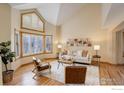 Cozy living room featuring a vaulted ceiling, large windows with shutters, and hardwood floors at 2215 Spotswood Pl, Boulder, CO 80304