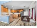 Open-concept kitchen featuring wood cabinetry, granite countertops, stainless appliances and a table with bench seating at 5209 Royal Pine St, Brighton, CO 80601