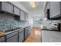 Bright kitchen with stainless steel sink, dishwasher, tiled backsplash, and hardwood floors at 546 Ridgeview Dr, Louisville, CO 80027