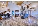 Open-concept living room with vaulted ceiling, hardwood floors, spiral staircase, piano, and large moose head at 6251 County Road 20, Longmont, CO 80504
