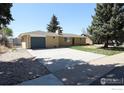 Ranch-style home with brick and siding, large driveway, and mature trees in a well-maintained yard at 845 10Th St, Berthoud, CO 80513