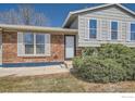 Close up view of a charming home showcasing the entry, red brick detail, and shuttered windows at 907 Stein St, Lafayette, CO 80026