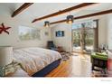Bright bedroom featuring hardwood floors, TV, and a glass sliding door leading to the backyard at 10978 W 82Nd Pl, Arvada, CO 80005