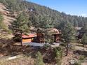 Expansive aerial view of a log home and garage surrounded by lush forest on a sloped lot in the mountains at 1280 N Cedar Brook Rd, Boulder, CO 80304
