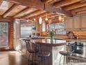 Bright kitchen featuring stainless steel appliances, custom cabinets, and a spacious island with bar seating under log beam ceilings at 1280 N Cedar Brook Rd, Boulder, CO 80304