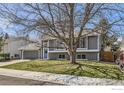 Exterior view of a grey two-story home with an attached garage and well-kept lawn on a sunny day at 145 S Buchanan Ave, Louisville, CO 80027