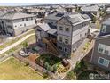 Aerial view of a home showcasing a spacious backyard, fire pit, deck, and white picket fence at 16335 Spanish Peak Way, Broomfield, CO 80023