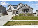 Charming two-story home with stone accents, a well-manicured lawn, and a welcoming front porch at 16335 Spanish Peak Way, Broomfield, CO 80023