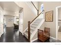 Inviting foyer with dark hardwood floors, staircase with white railings and stylish decor at 16848 Weber Way, Mead, CO 80542