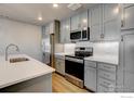 Updated kitchen features stainless steel appliances, gray cabinets, white subway tile backsplash, and a modern faucet at 235 High Point Dr # 103, Longmont, CO 80504