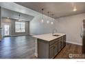 Kitchen features gray cabinets, quartz countertop island, stainless steel appliances, and three stylish pendant lights at 235 High Point Dr # 103, Longmont, CO 80504